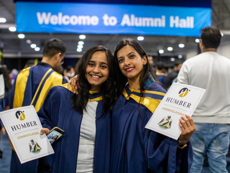 Two graduates posing for photo in Alumni hall