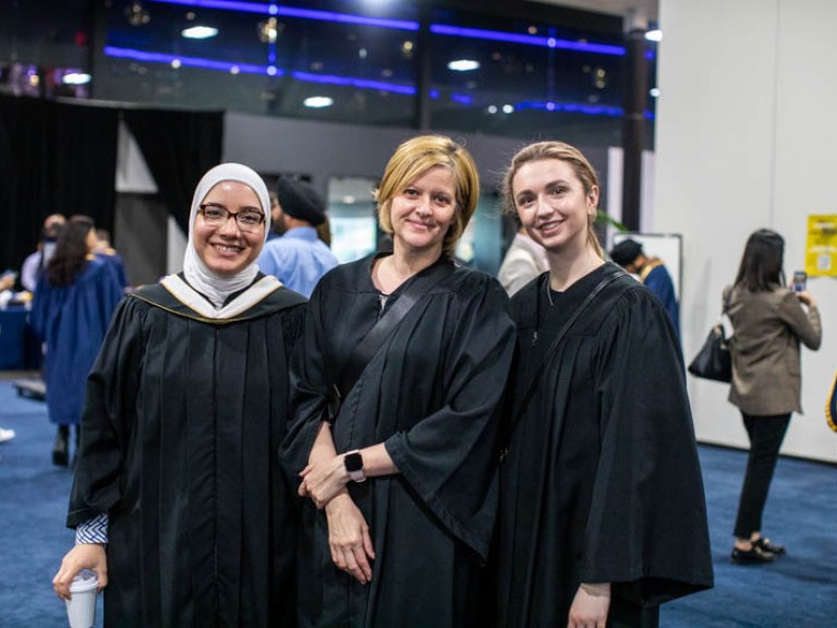 Three people in black robes smiling at camera