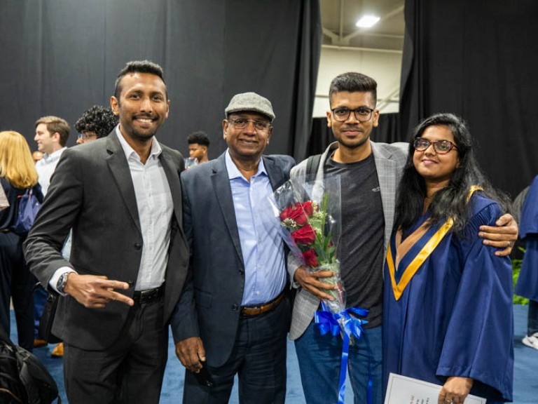 Graduate poses for photo with ceremony guests