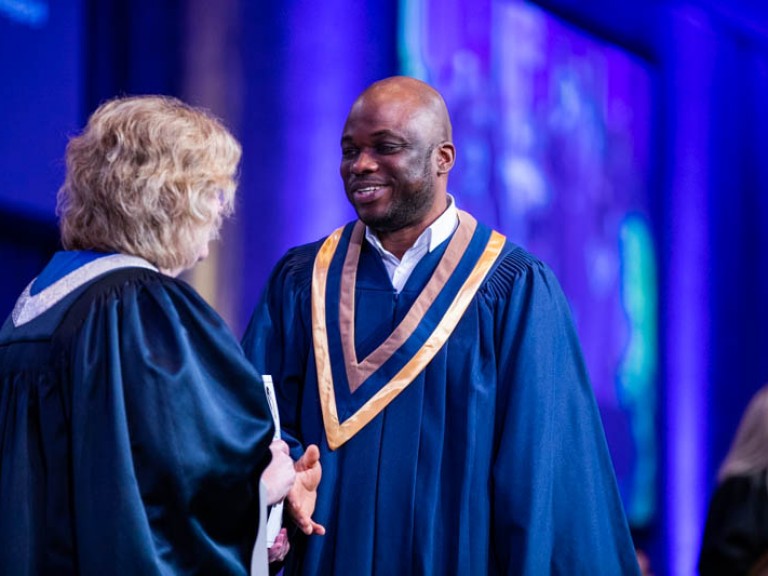 Graduate on stage looking at Ann Marie Vaughan