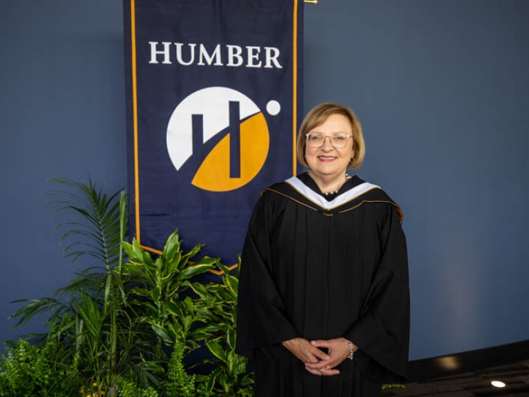 Honorary degree recipient Lana Payne posing for photo in front of Humber flag