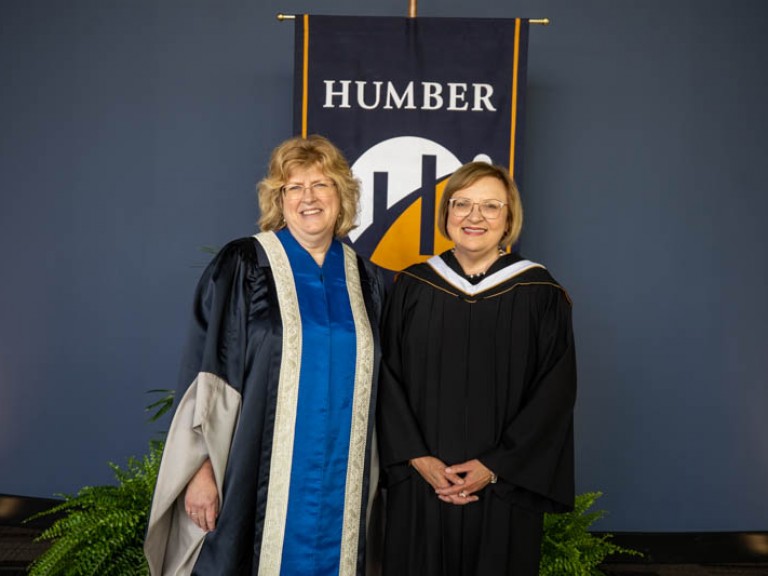 Lana Payne and Ann Marie Vaughan pose for photo in front of Humber flag