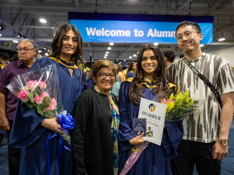 Two graduates holding flowers posing for photo with family