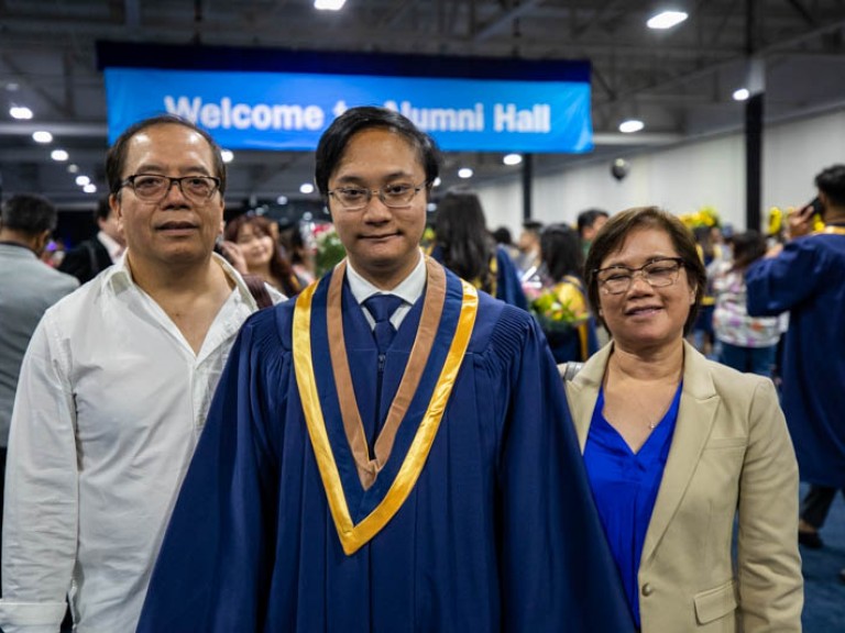 Graduate poses for photo with his parents