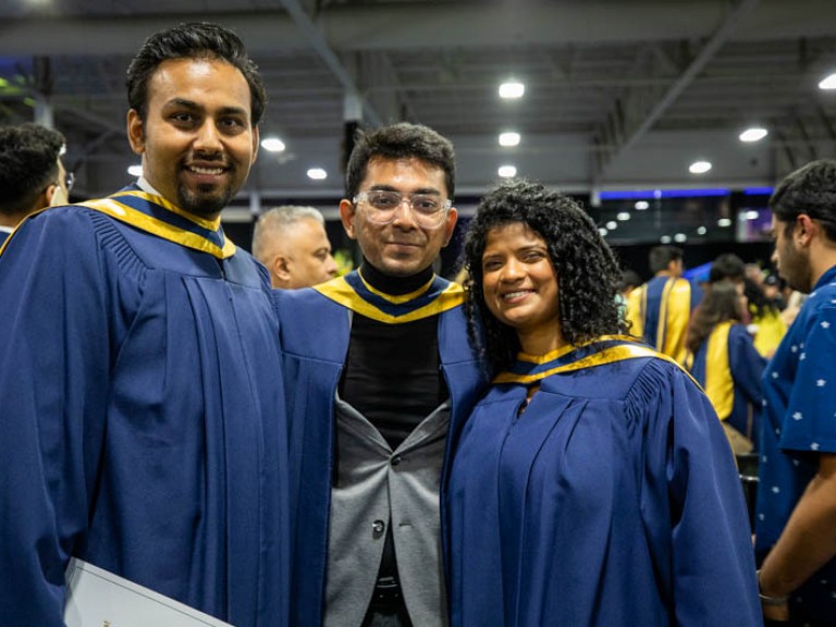 Three graduates posing for photo in reception area