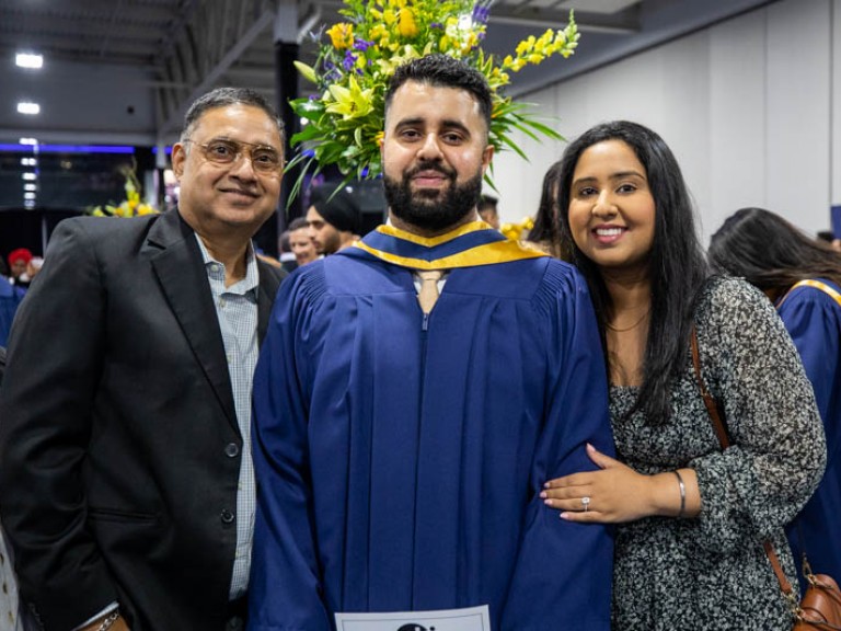 Graduate poses for photo with two ceremony guests