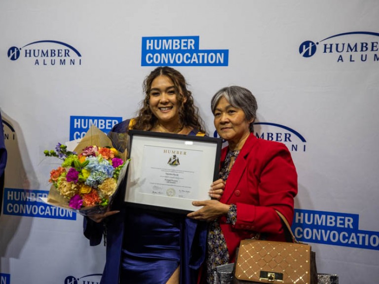 Graduate holding framed award with family member
