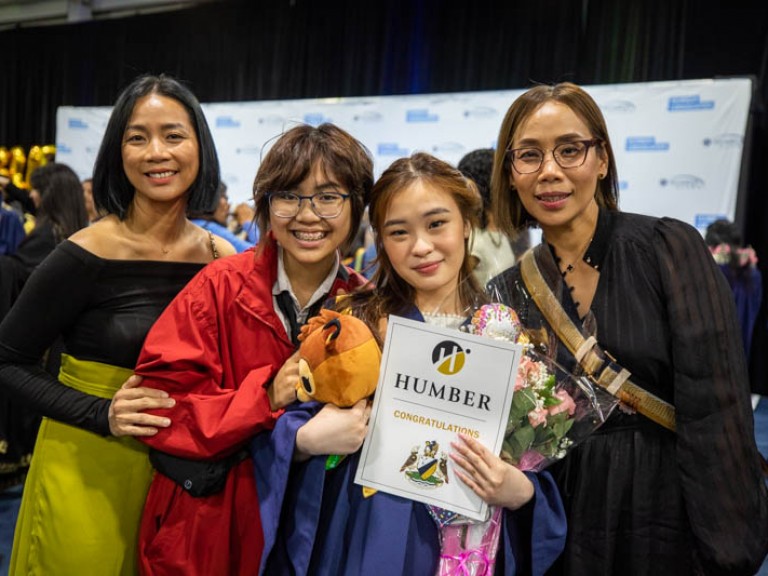 Graduate posing for photo with three guests