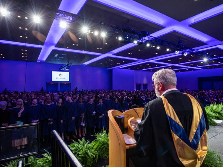 View of graduates in audience from behind podium speaker