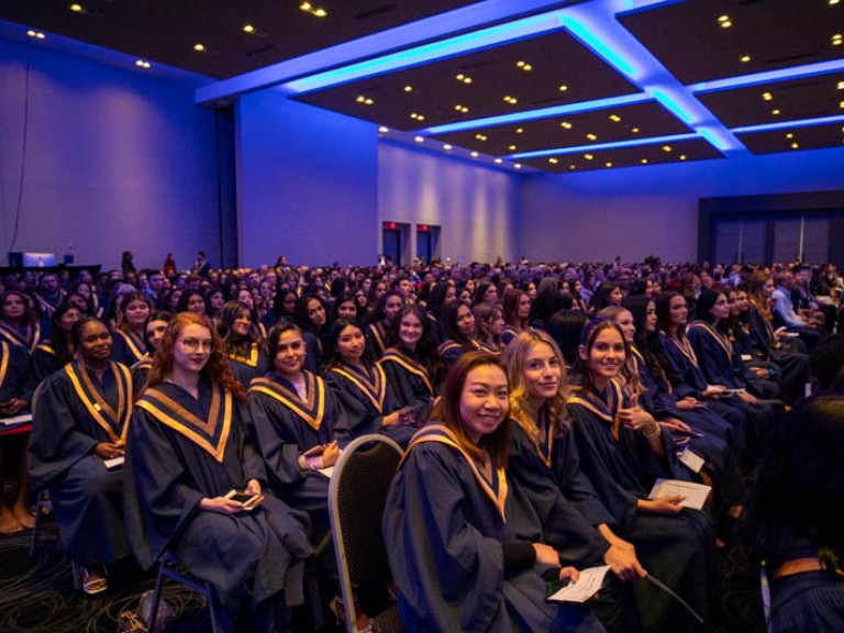 Graduates seated in audience look at camera