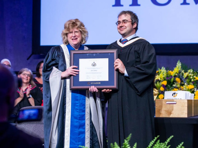 Honorary degree recipient and Humber president Ann Marie Vaughan holding framed degree between them