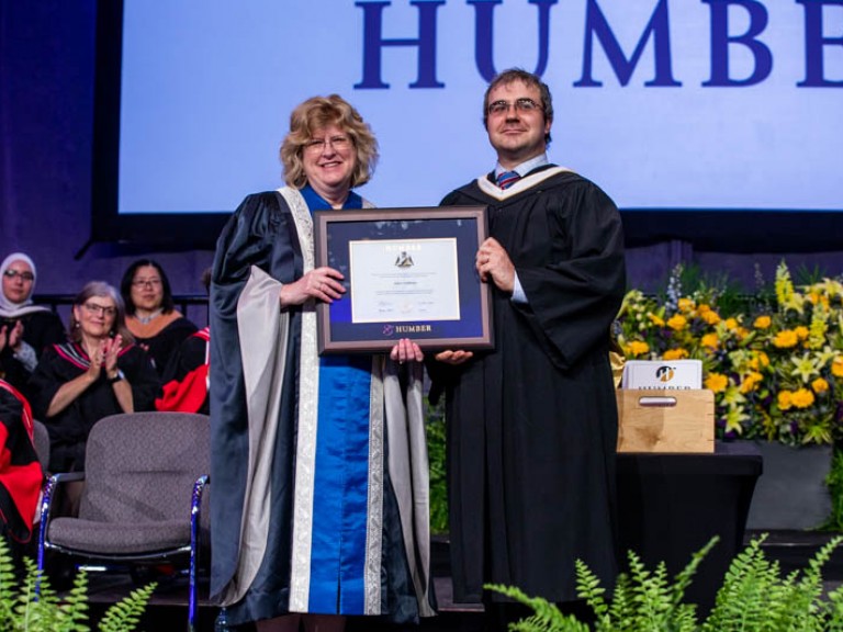 Honorary degree recipient and Humber president Ann Marie Vaughan holding framed degree between them