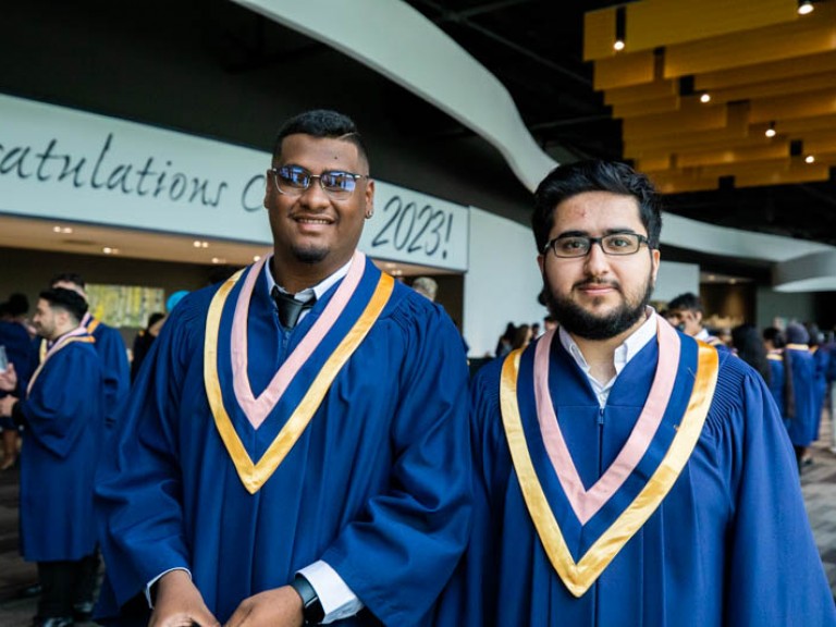 Two graduates posing for photo in reception hall