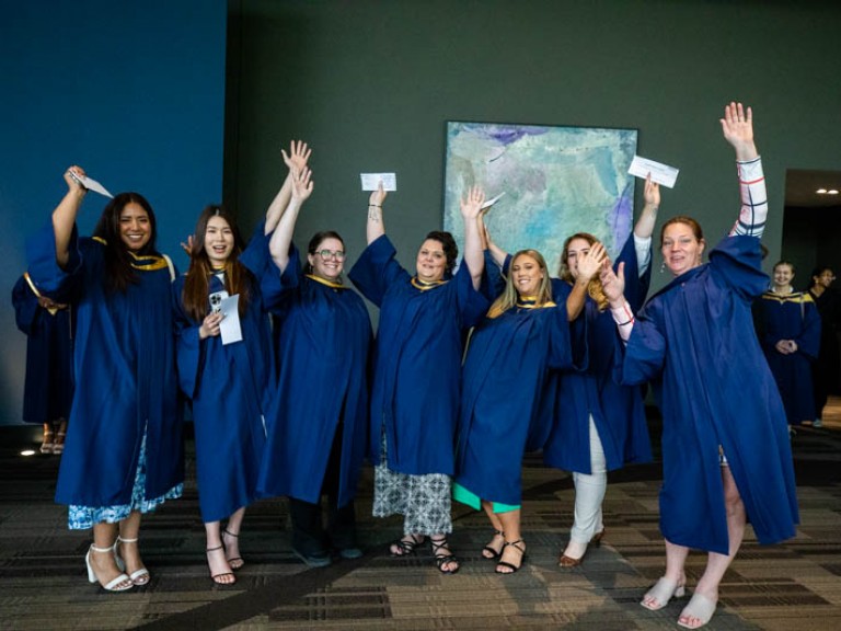 Seven graduates raise hands in celebration