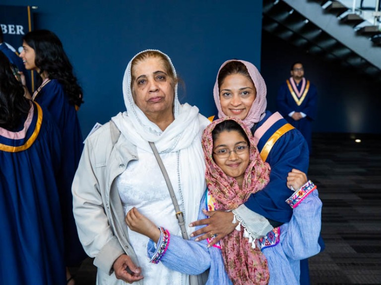 Graduate posing for photo with two family members