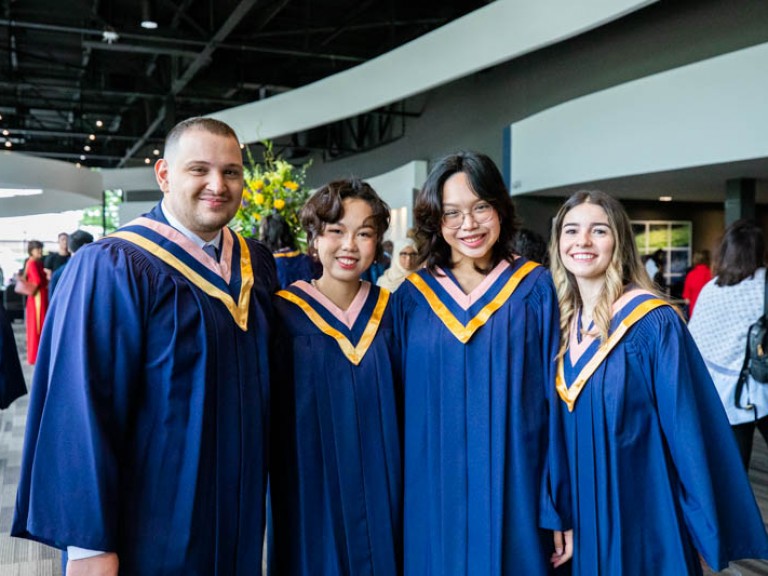 Four graduates pose for photo in reception hall