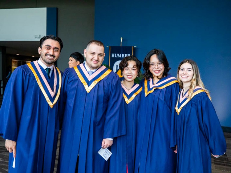 Five graduates pose for photo in reception hall