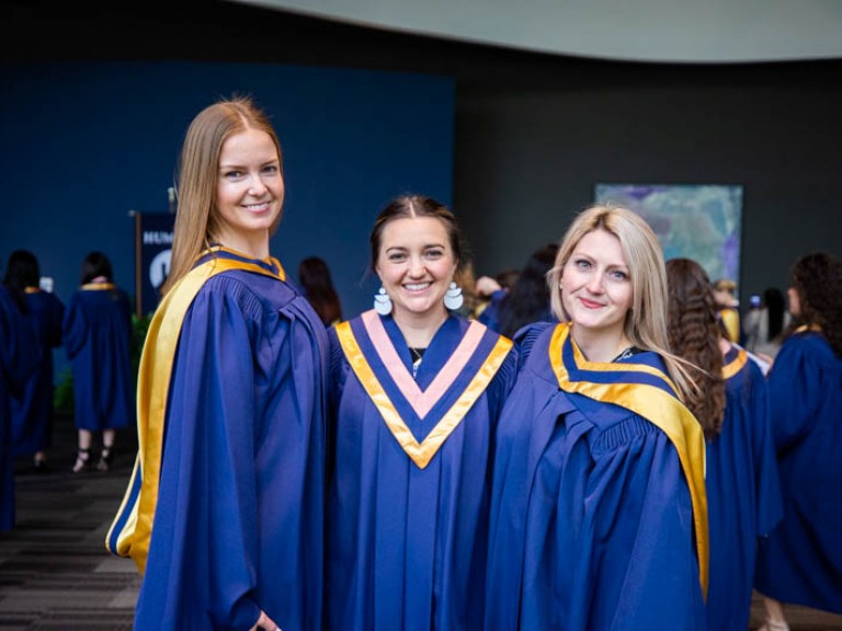 Three graduates pose for photo