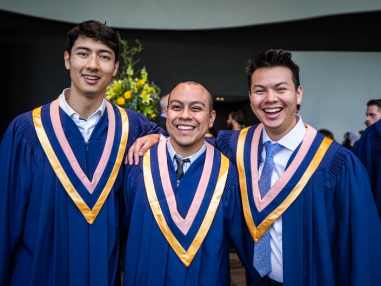 Three graduates smile for camera