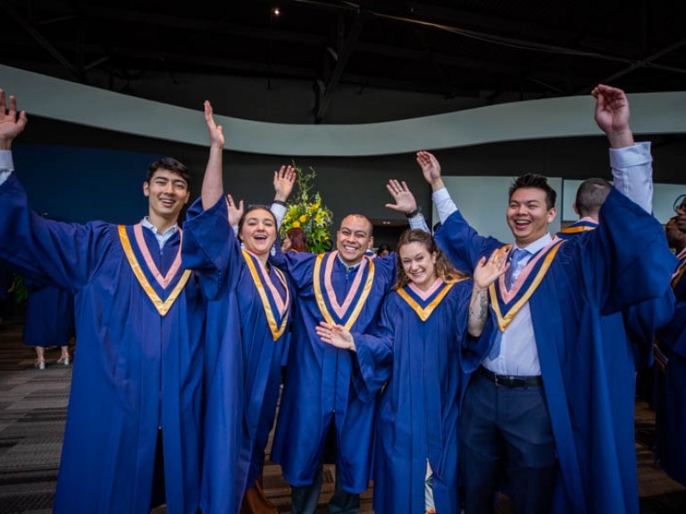 Five graduates raise arms in celebration