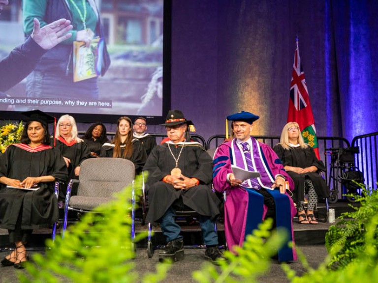 Elder Albert Marshall sitting on stage with faculty