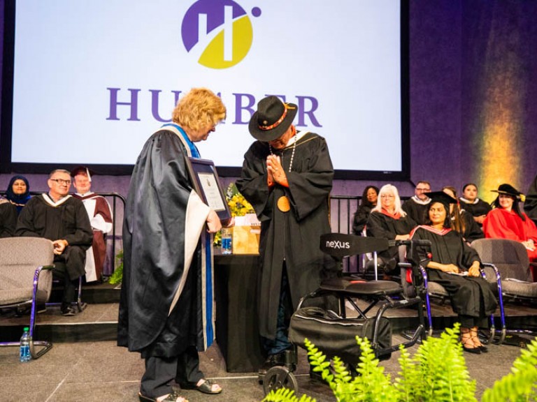 Elder Albert Marshall bows his head with hands together in front of Ann Marie Vaughan