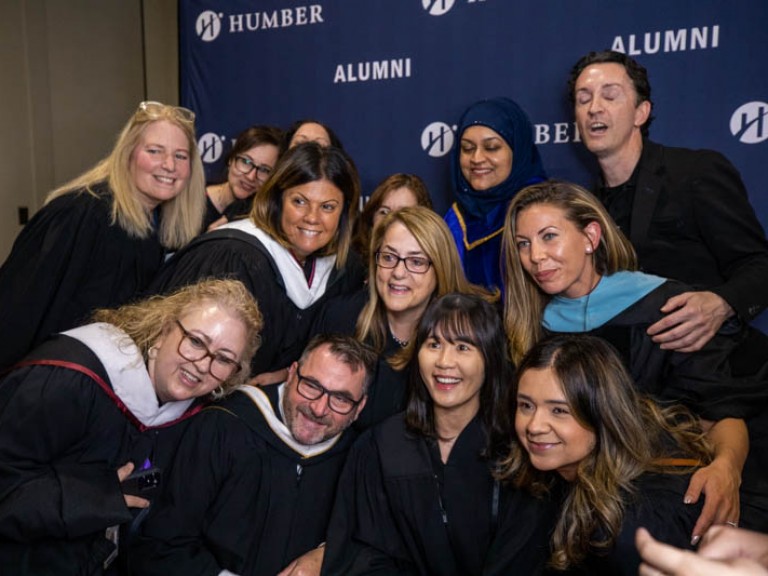 Group of people talking photo in front of Humber Alumni wall