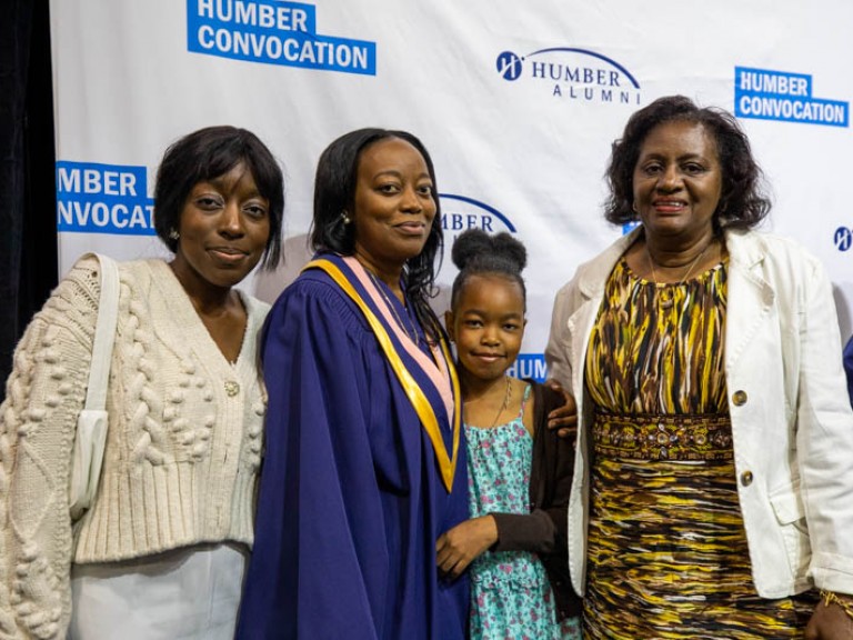 Graduate poses for photo with three family members