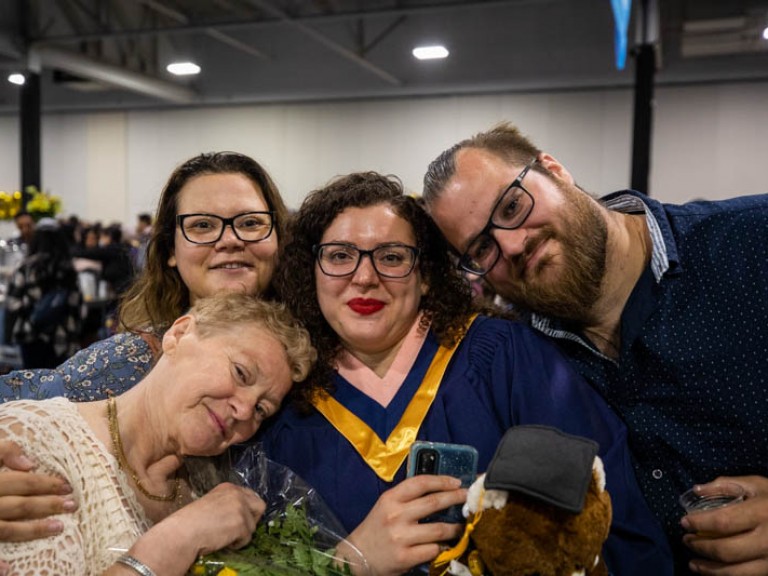 Graduate with three family members hugging her close