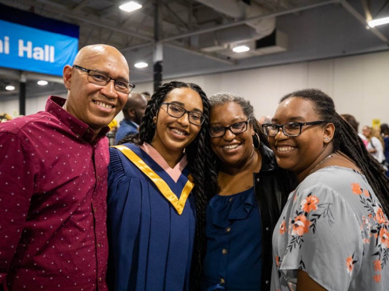 Graduate and three family members smile for camera