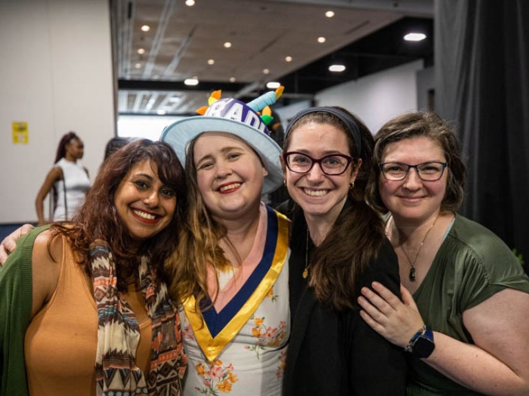 Graduate smiles for camera with three guests