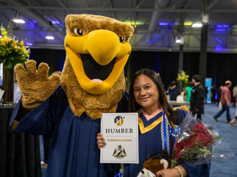 Graduate takes photo with Humber mascot