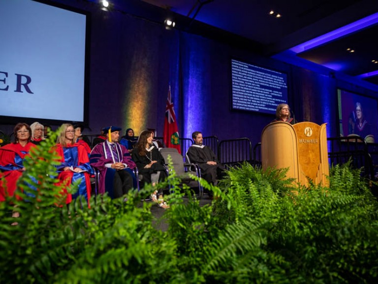 Faculty seated on stage looking at podium speaker