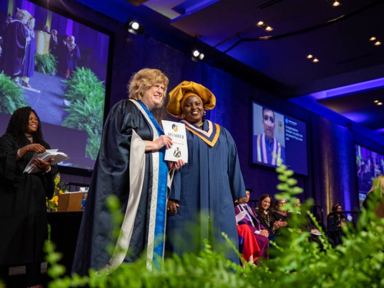 Graduate and Ann Marie on stage pose for photo