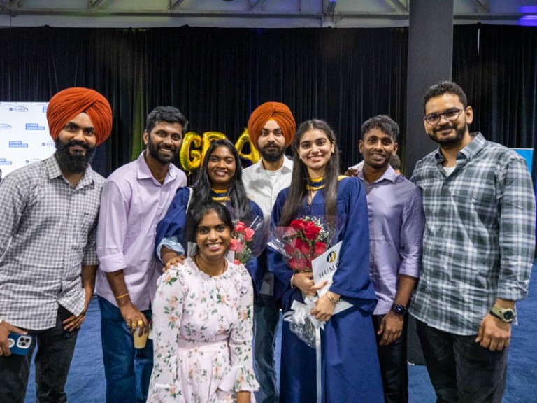 Two graduates take photo with ceremony guests