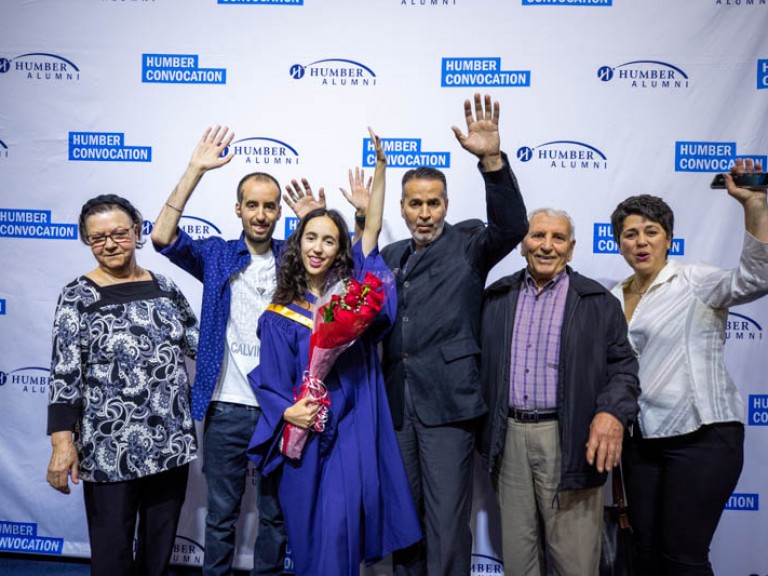 Graduate and family raise arms in celebration