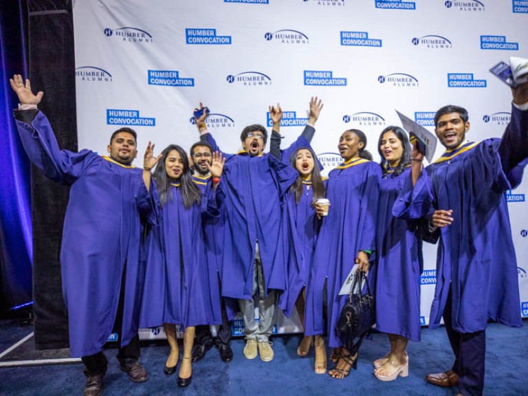 Eight graduates raise arms in celebration