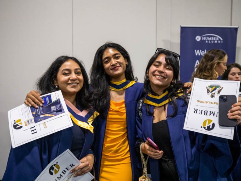 Three graduates smile for photo