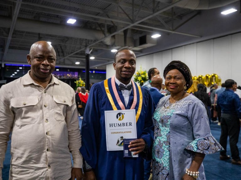 Graduate poses for photo with parents