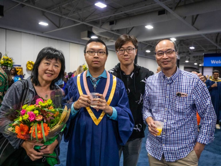 Graduate and three family members pose for photo