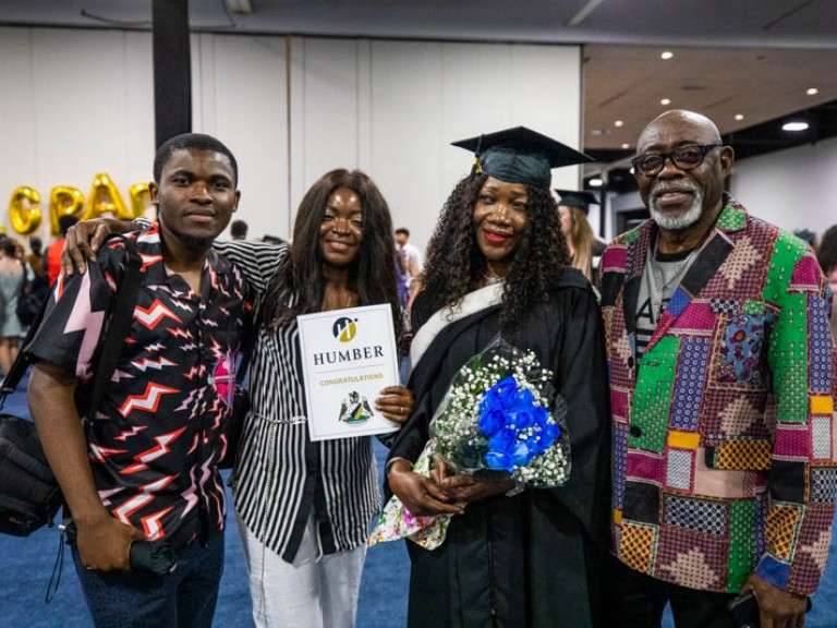 Graduate holding flowers takes photo with family