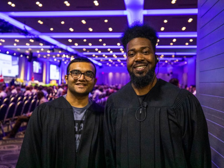 Two people in black robes smiling