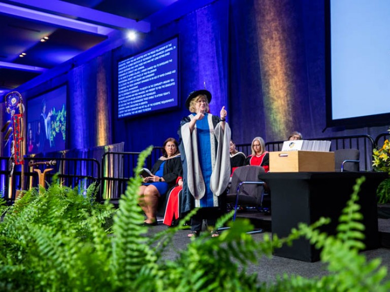 Humber president Ann Marie Vaughan holding thumbs up on stage