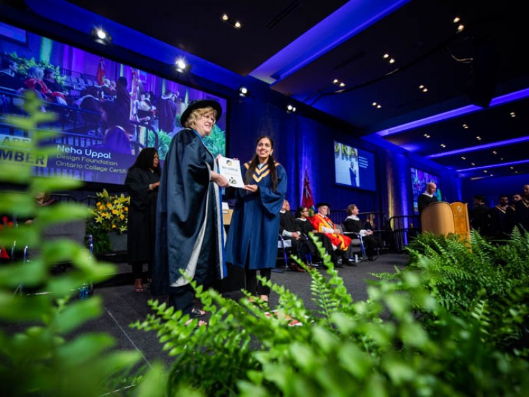 Graduate and Ann Marie smile for photo on stage