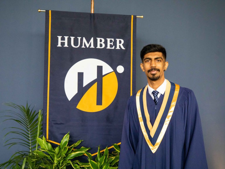 Graduate beside Humber flag