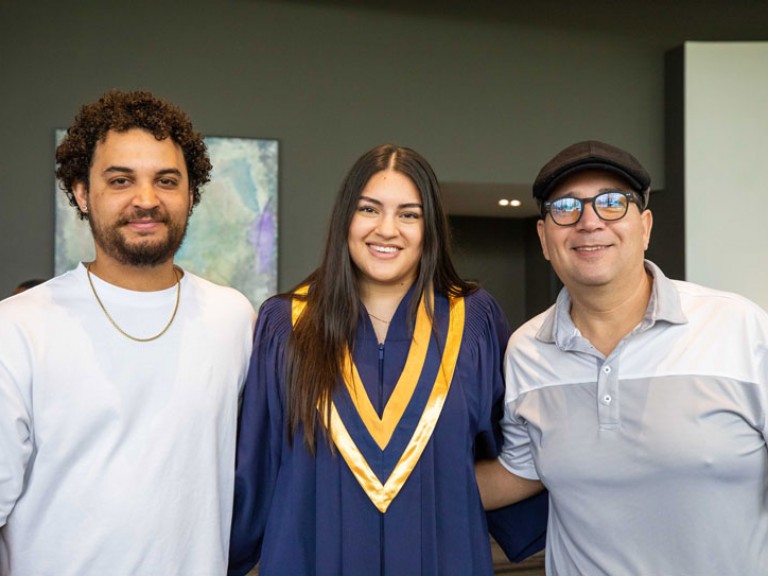 Graduate poses for photo with two guests