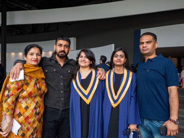 Two graduates take photo with three guests