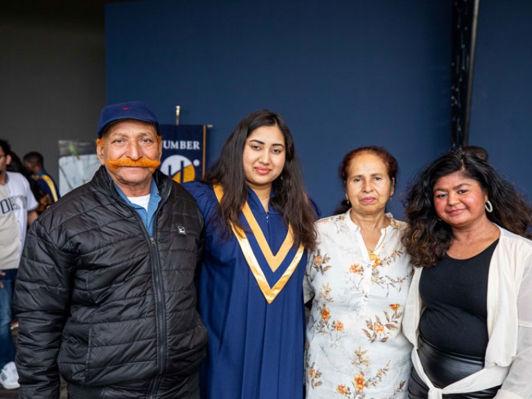 Graduate poses for photo with three guests