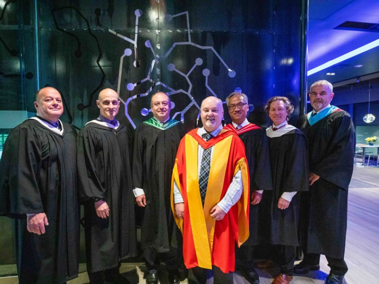 Seven faculty members in robes pose for photo