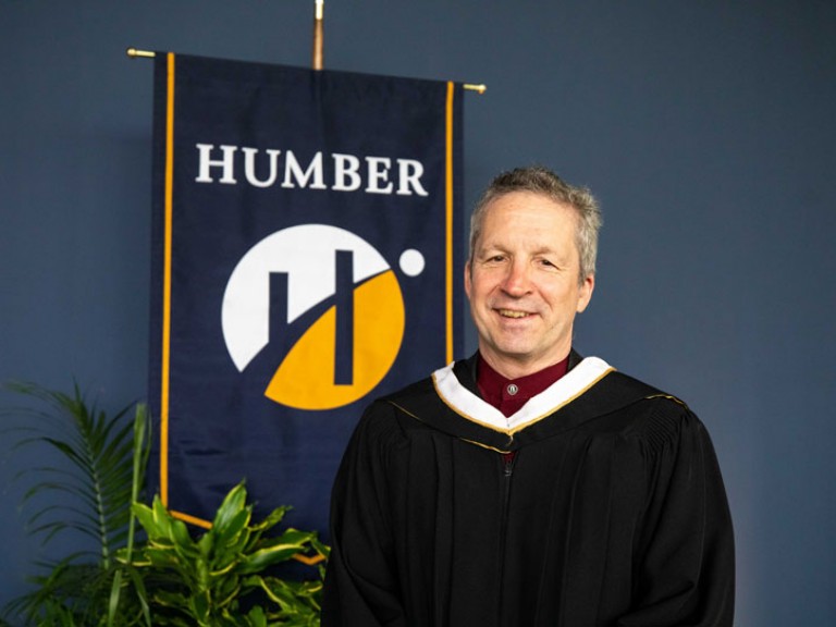 Jim Estill poses for photo in front of Humber flag